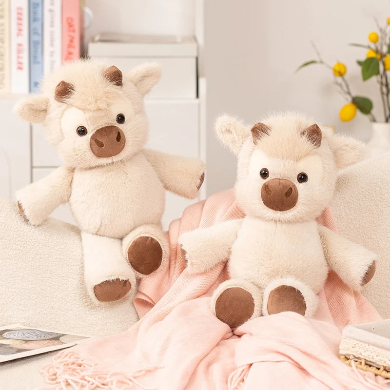 Two cow plushies on a sofa with a pink blanket