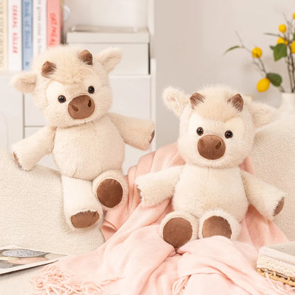 Two cow plushies on a sofa with a pink blanket