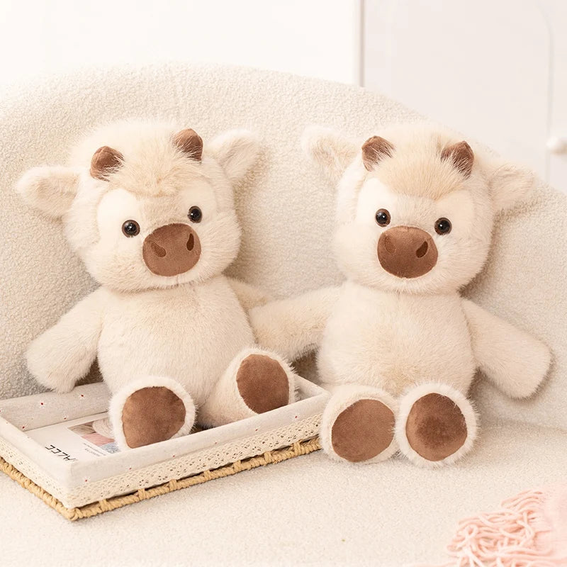 Two cow plushies sitting on a sofa